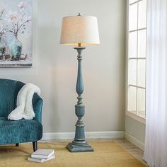 a living room with a blue chair, lamp and painting on the wall behind it