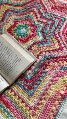 an open book laying on top of a crocheted blanket