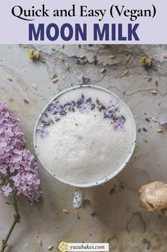 a cup filled with milk next to some flowers