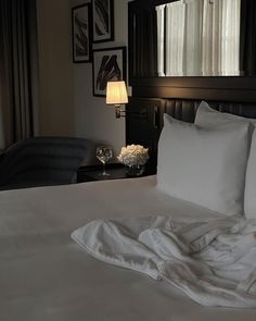 a bed with white sheets and pillows in a hotel room