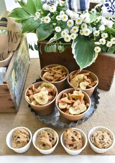 there are many cookies and muffins on the table with flowers in the background