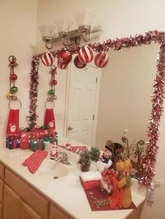 a bathroom decorated for christmas with ornaments on the counter and decorations hanging from the mirror