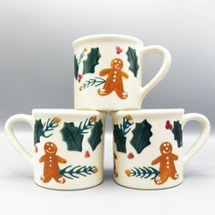 three mugs decorated with ginger cookies and holly leaves