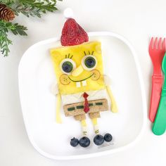 a white plate topped with a cartoon character next to a plastic fork and spoons