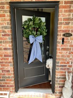 a dog is standing in front of a door with a bow on it's head