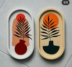 two trays with designs on them sitting on the floor next to each other and one has a plant in it