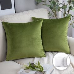 two green pillows sitting on top of a white couch next to a potted plant