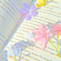 an open book with flowers on it and the pages are white, pink, yellow and blue