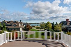 a white fenced in area with houses and water in the backgrouds