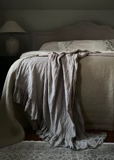 an unmade bed with two lamps on either side and a blanket draped over it