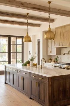 a large kitchen with an island in the middle and two pendant lights hanging from the ceiling