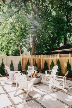 an outdoor patio with white chairs and fire pit