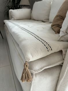 a white couch with some pillows and a plant in the corner on top of it