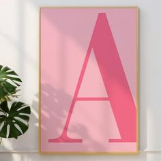 a pink poster with the letter a on it next to a potted plant