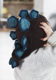 a young child wearing a knitted hat with blue flowers on the front and back