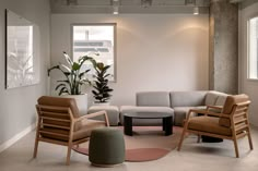 a living room filled with furniture next to a window and potted plant in the corner