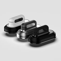 three black and white earbuds sitting next to each other on a gray surface