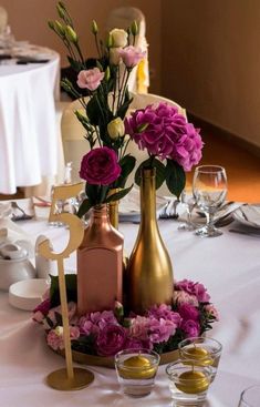 the table is set with wine glasses and vases filled with flowers, candles and decorations