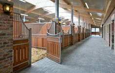 the inside of a building with wooden stalls and brick walls on either side of it