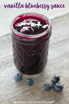 blueberry sauce in a glass jar with berries around it