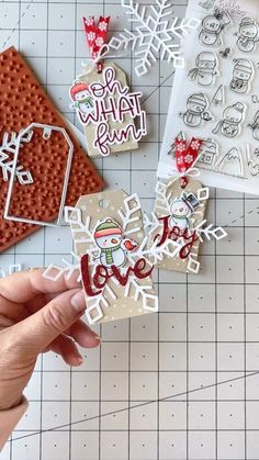 someone is holding up some christmas decorations on a table with other items in the background