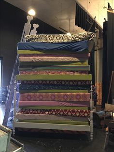 a stack of pillows sitting on top of a wooden chair in front of a stage