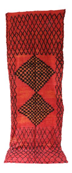 an orange and black piece of cloth with geometric designs on the edges, hanging from a white wall