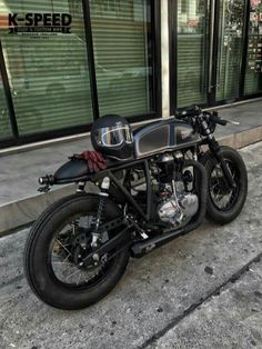 a black motorcycle parked in front of a building on the side of a street with windows