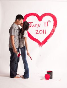 a man and woman kissing in front of a heart painted on the wall