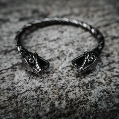 a close up of a snake head ring on a stone surface