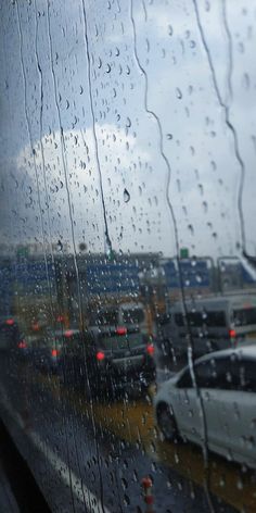 rain drops on the windshield of an airplane as it is parked in front of a terminal