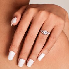 a woman's white manicured nails with a diamond ring on her left hand