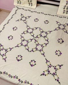 a white bed with purple flowers on it