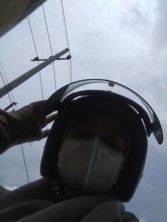 a person wearing a face mask while sitting in a chair with wires above them and the sky behind him