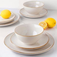 a white table topped with plates and bowls filled with lemons on top of it