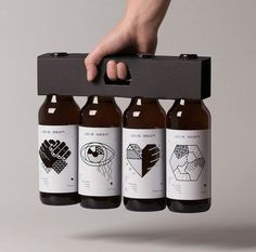 four beer bottles with different designs on them being held by a person's hand