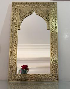 a mirror that is on top of a table with flowers in the vase next to it