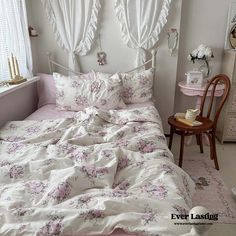 a bed with pink and white flowers on it in a bedroom next to a window