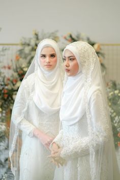 two women dressed in white standing next to each other