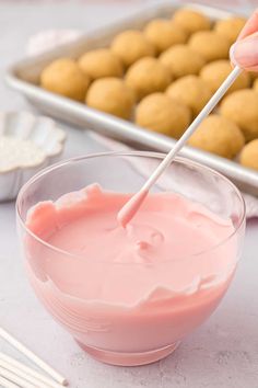 a person dipping something in a bowl with a toothpick on top of it