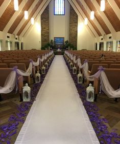 the aisle is decorated with purple and white flowers