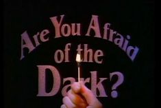 a person holding a lit matchstick with the words are you afraid of the dark?