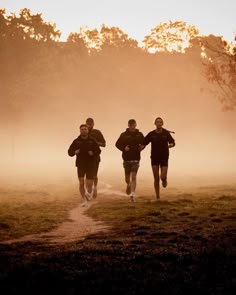 three men are running in the foggy field