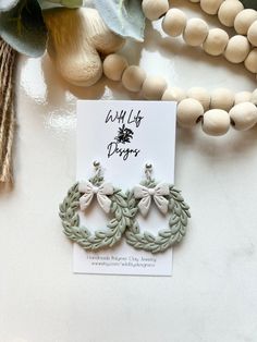 a pair of earrings sitting on top of a table next to some beads and flowers