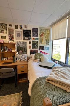 a bed sitting in a bedroom next to a window with lots of pictures on the wall