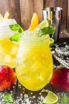 two glasses filled with lemonade, lime and mint on top of a wooden table