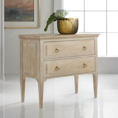 a white dresser with two drawers and a vase on top