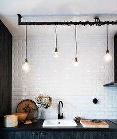 a kitchen with white brick walls and lights hanging from the ceiling