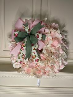 a wreath with pink and white flowers is hanging on a door handle in front of a wall