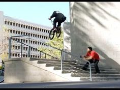 a man riding a bike up the side of a flight of stairs next to a building